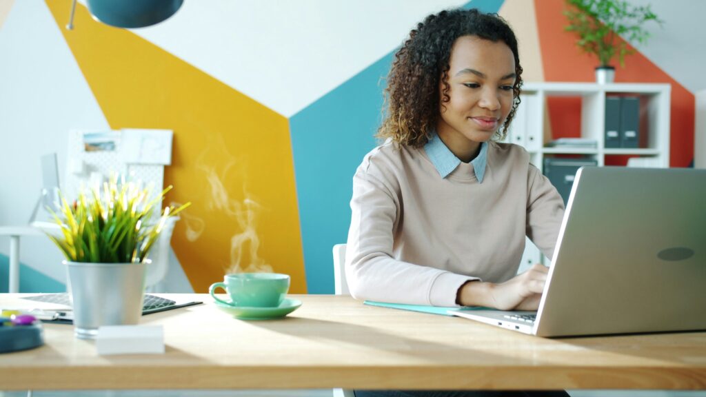 Woman is sitting in front of a laptop smiling
